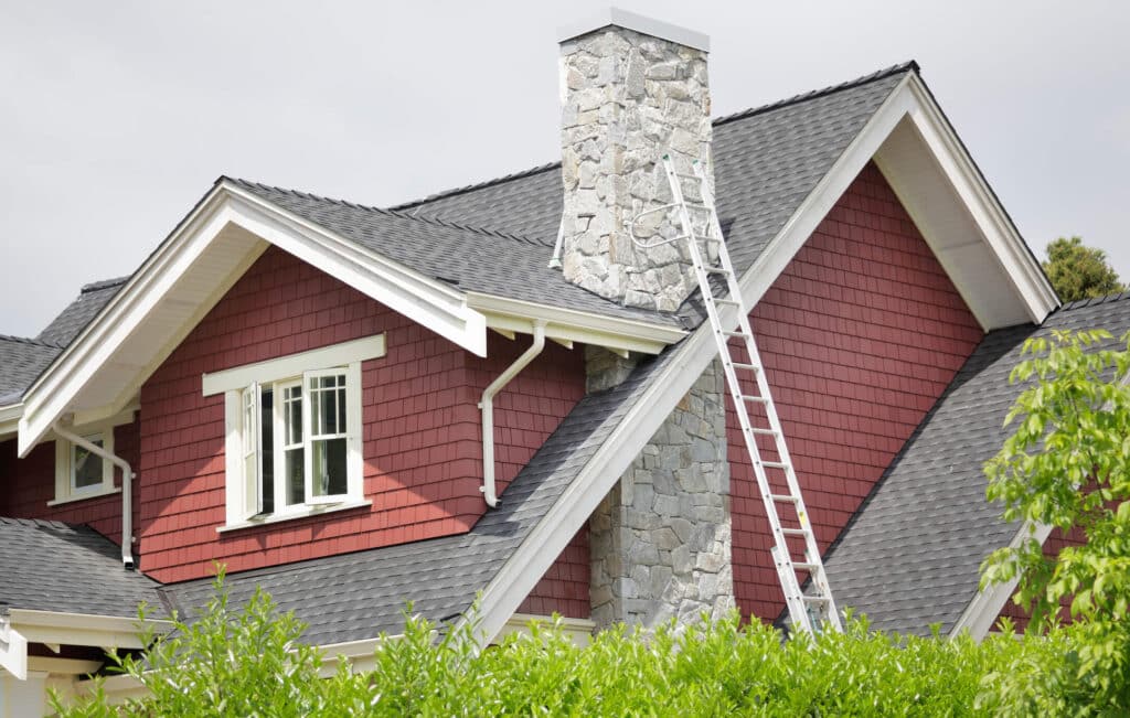 a small red house with a ladder up to the roof