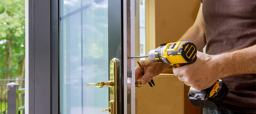 person using a drill to screw in a door frame