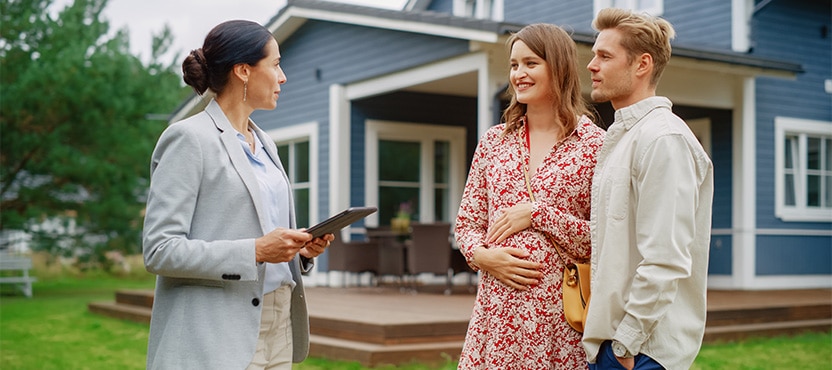 a man and a woman talk to an architect in front of a house