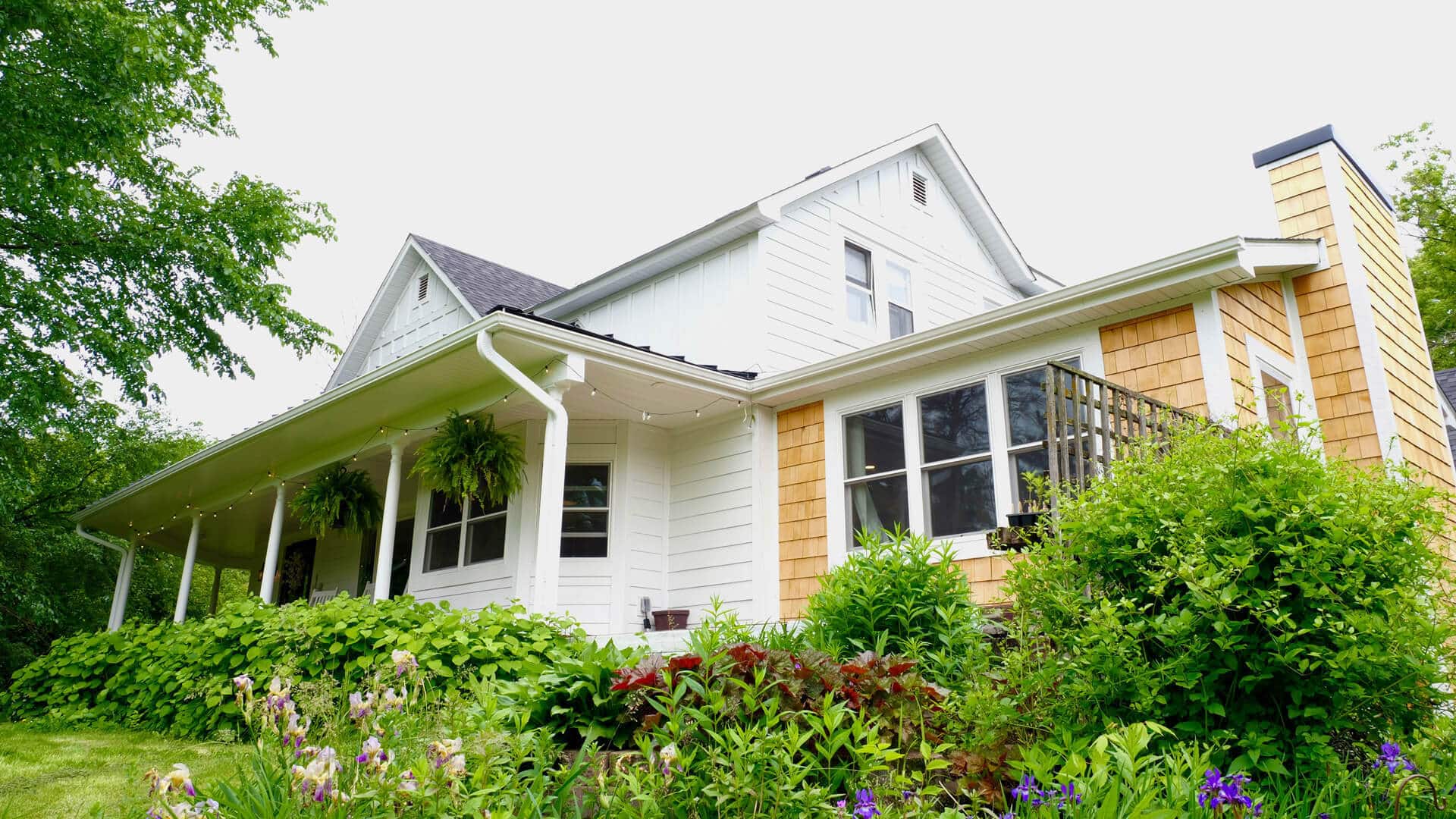 a nicely finished residential house with beautiful new siding, a new roof, and abundant gardens